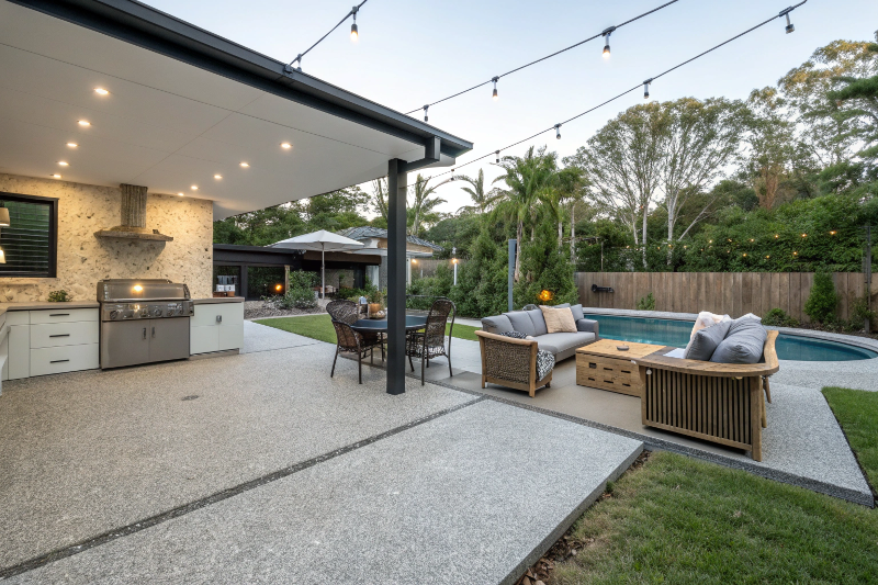 Exposed aggregate concrete patio with outdoor furniture and BBQ area in Fraser Coast backyard